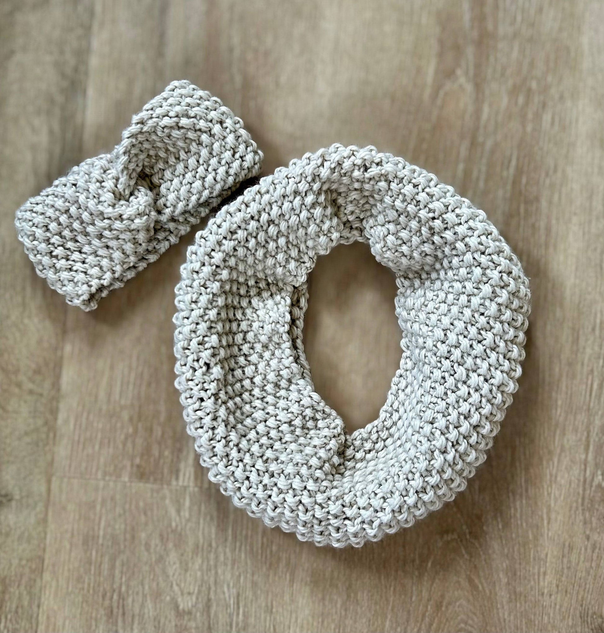 Knitted light gray headband and cowl set on a wooden surface.