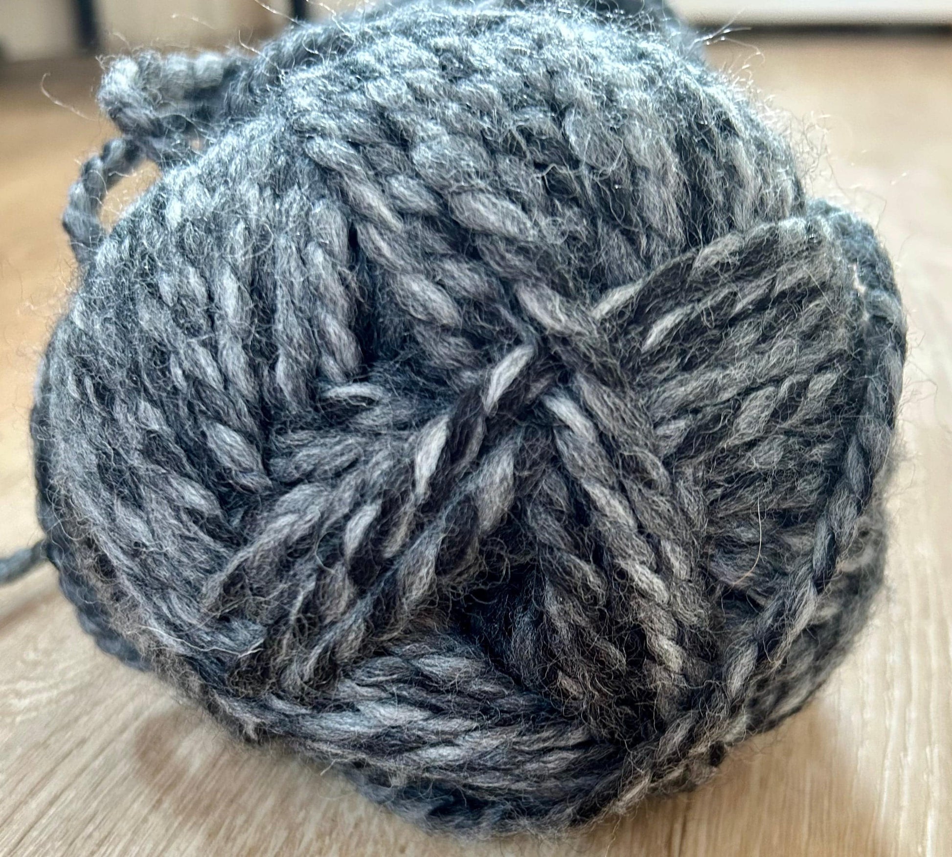 Close-up of a gray ball of yarn on a wooden surface for the cowl and ear-warmer set
