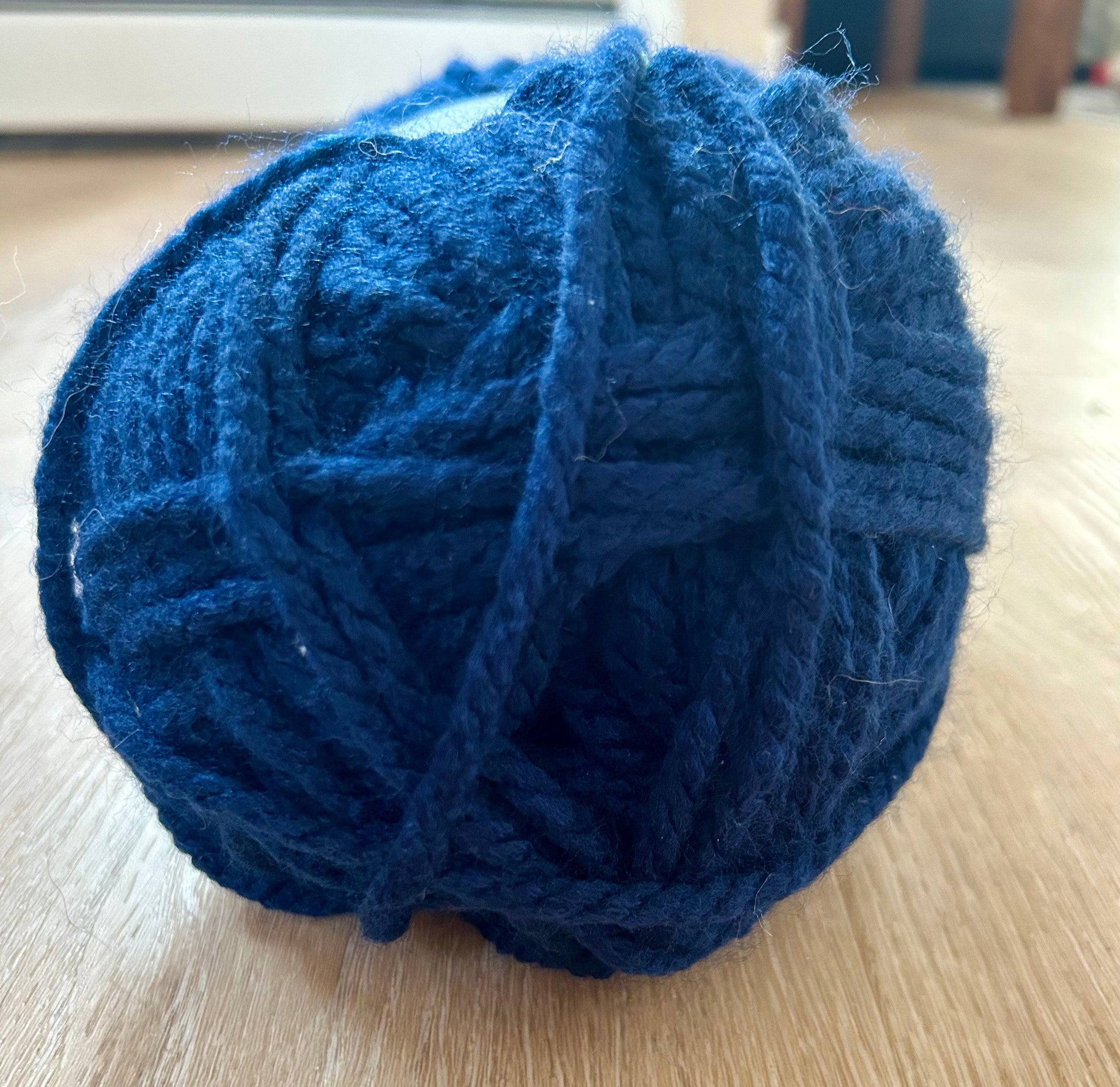 Close-up of a blue ball of yarn on a wooden surface.